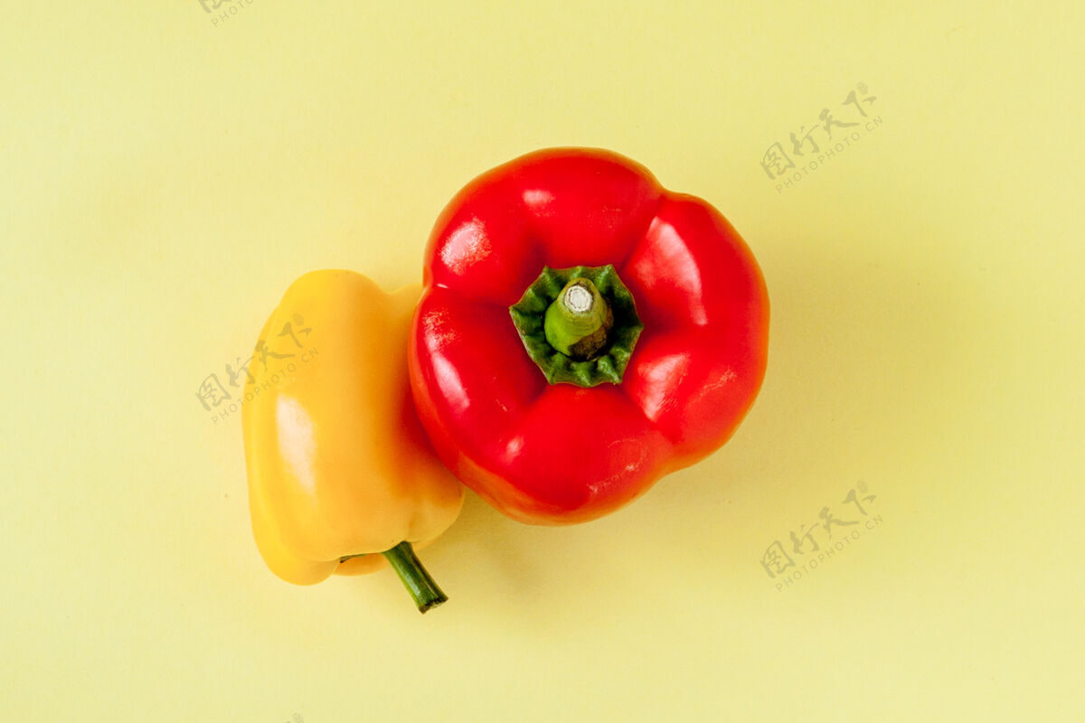 辣椒整个黄色和红色的甜椒或辣椒在黄色背景上。五颜六色有机配料