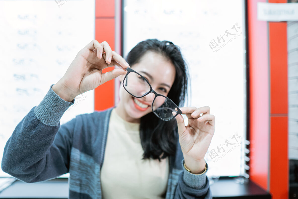 眼科医生一个美丽的女人拿着一个眼镜样品在一个眼镜展示窗口的背景眼镜诊所年轻医学视觉