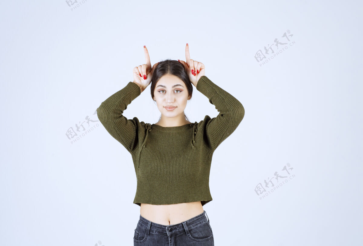 情绪一个年轻有趣的女模特站着用手指展示兔子耳朵的画像有趣兔子女性