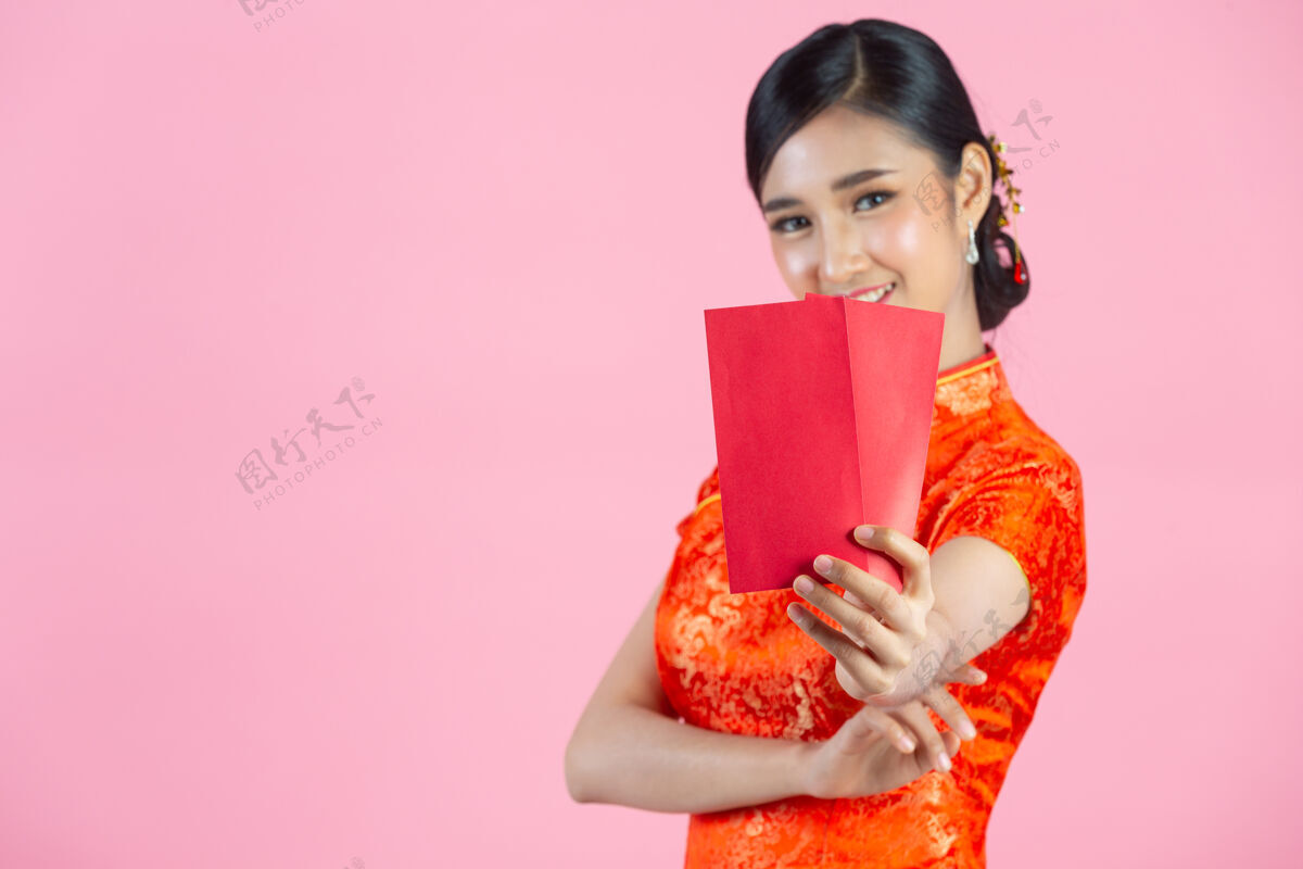 空美丽的亚洲女人在中国的新年里展示一些东西和拿红包年轻微笑年