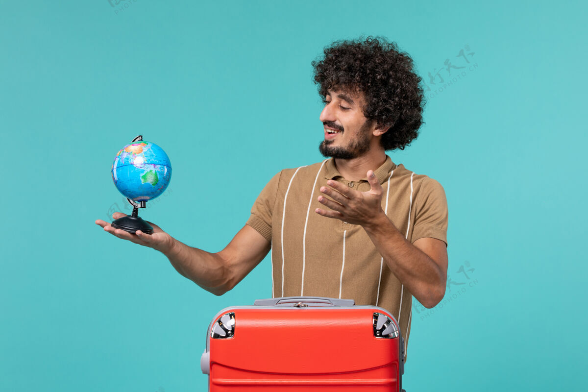 红色度假的人手里拿着一个蓝色的红色袋子的小地球仪旅行成人旅程