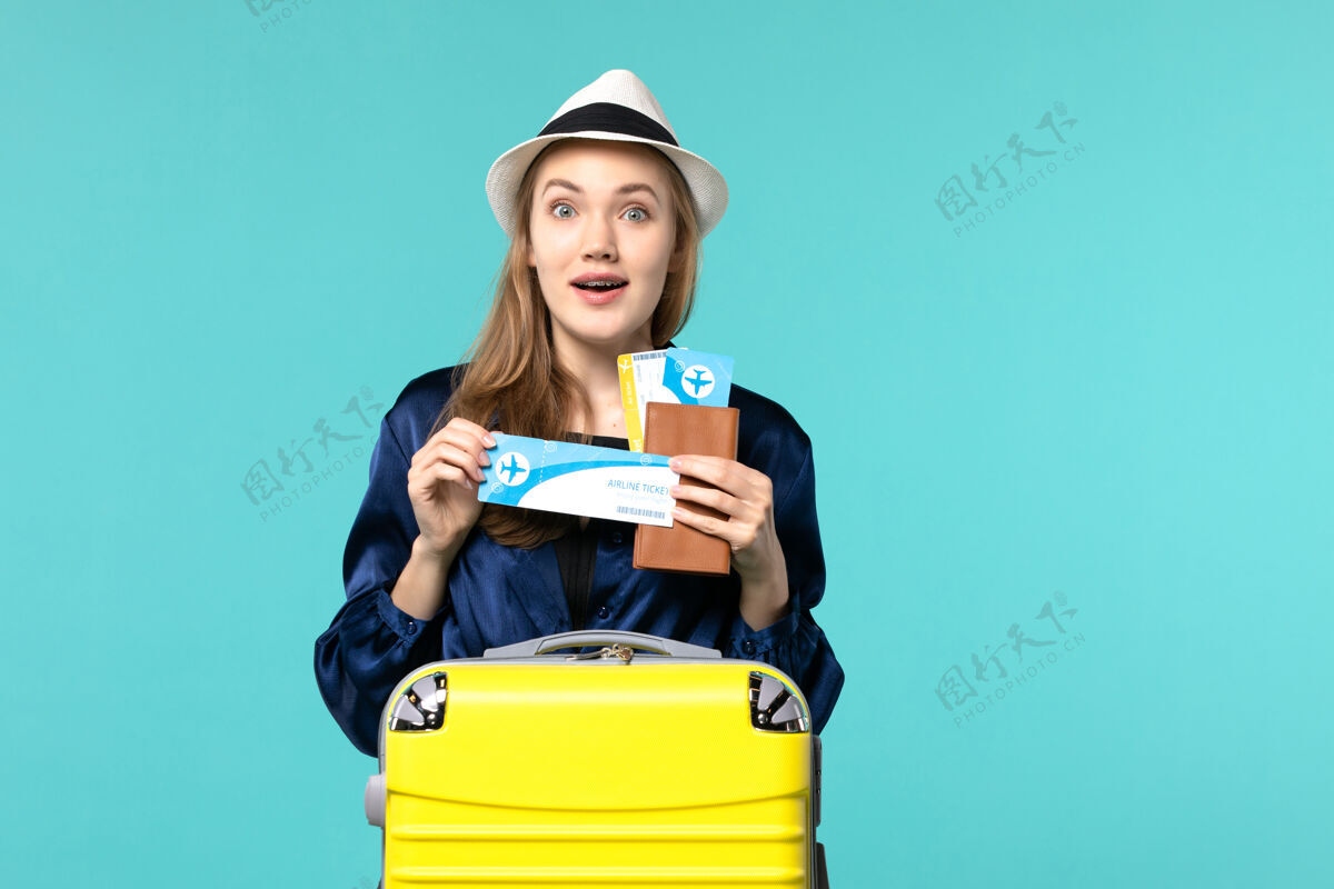 美丽正面图年轻女子拿着机票 准备乘坐蓝色背景的旅行飞机海上度假旅行肖像旅行旅行