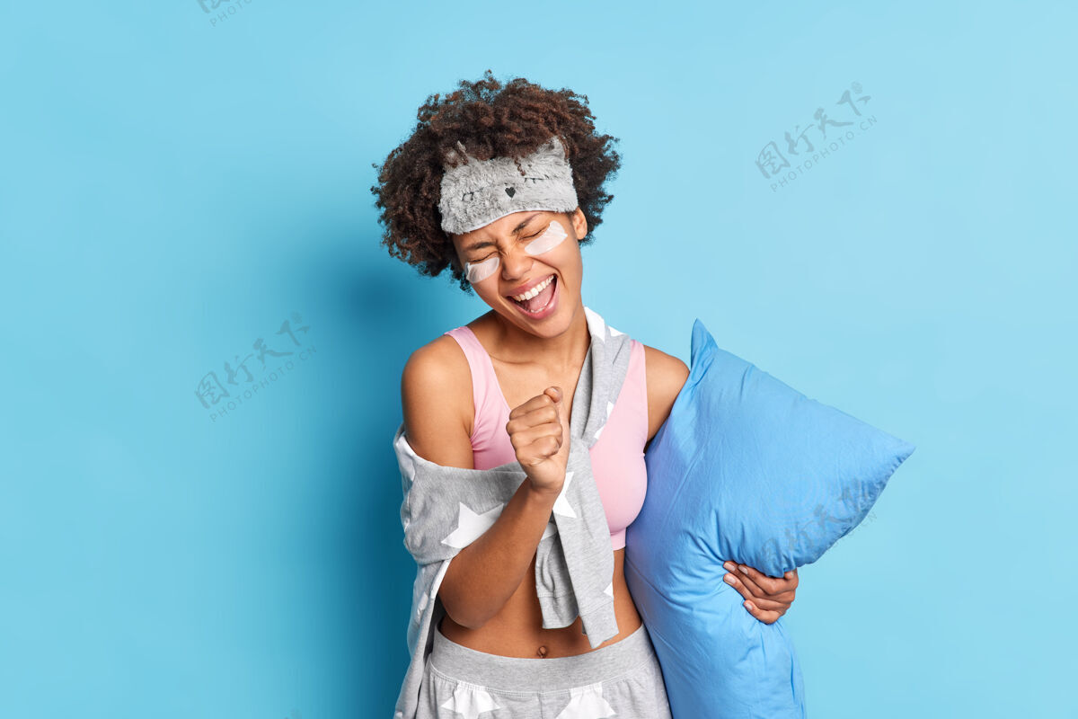 请喜出望外的女人唱着歌 手挽着手 好像麦克风很有趣 穿着睡衣 抱着柔软的枕头 隔着蓝色的墙壁放松补丁满足