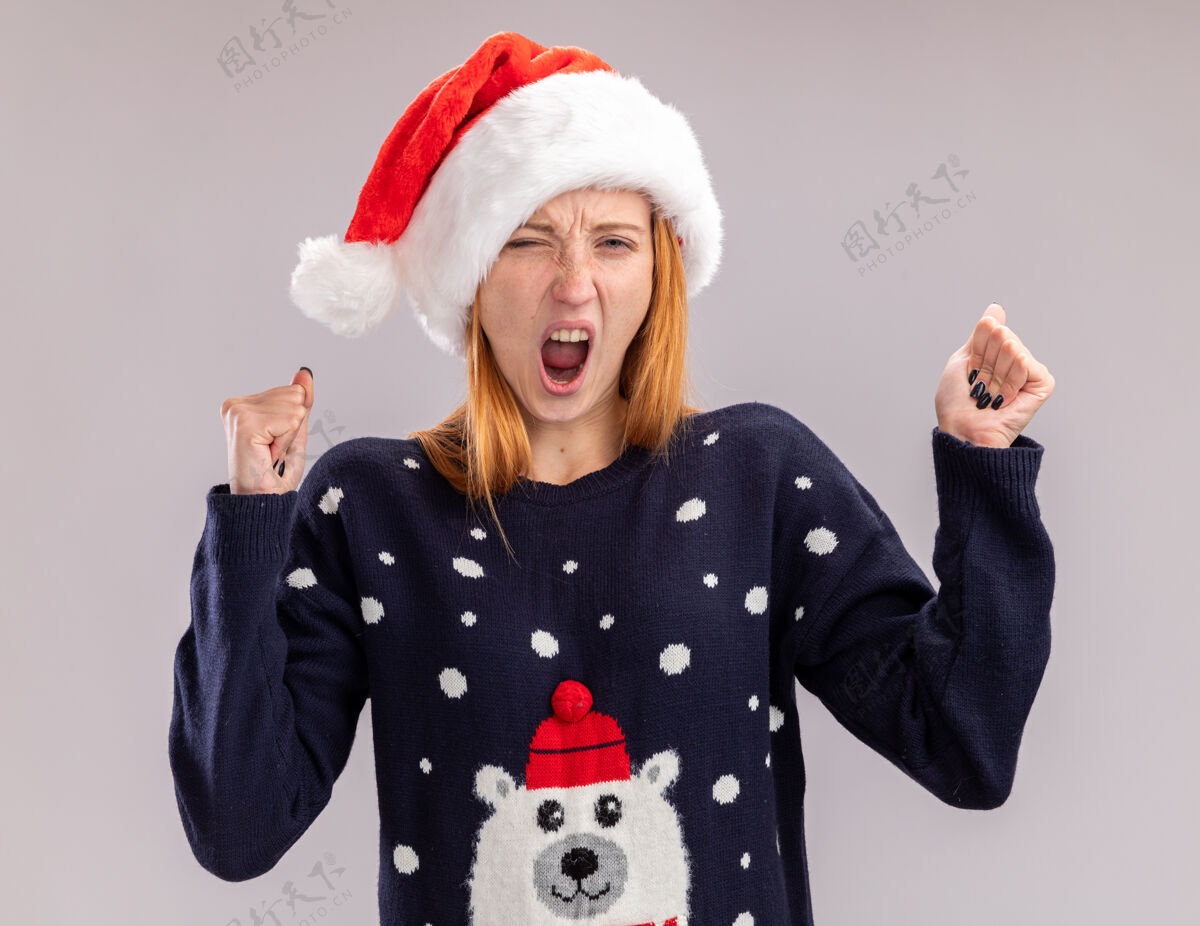 是的兴奋的年轻漂亮女孩戴着圣诞帽 在白色背景上显示“是”的手势表演圣诞快乐白色