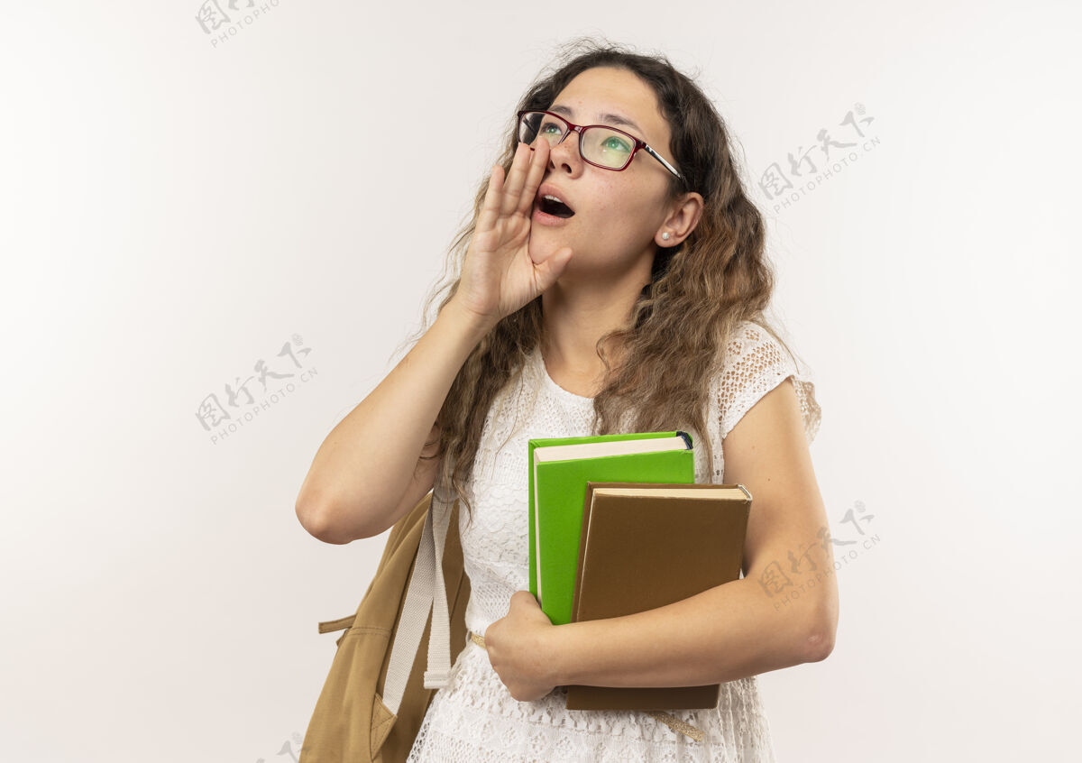 嘴年轻漂亮的女学生戴着眼镜 背着书包 抬起头 把手放在嘴边 对着一个被隔离在白色背景下 留着复印空间的人喊道抱有人背