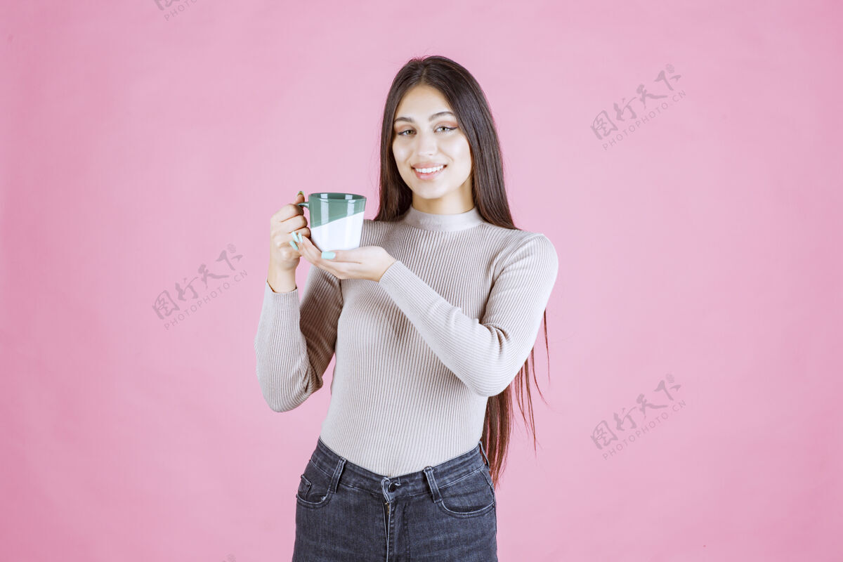 装备女孩拿着一个白绿色的咖啡杯 感觉很积极女人热茶