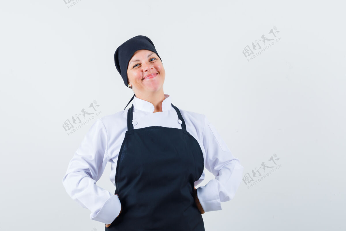 手金发女人手放在腰上 穿着黑色厨师制服 看起来很漂亮 正面视图美女模特皮肤