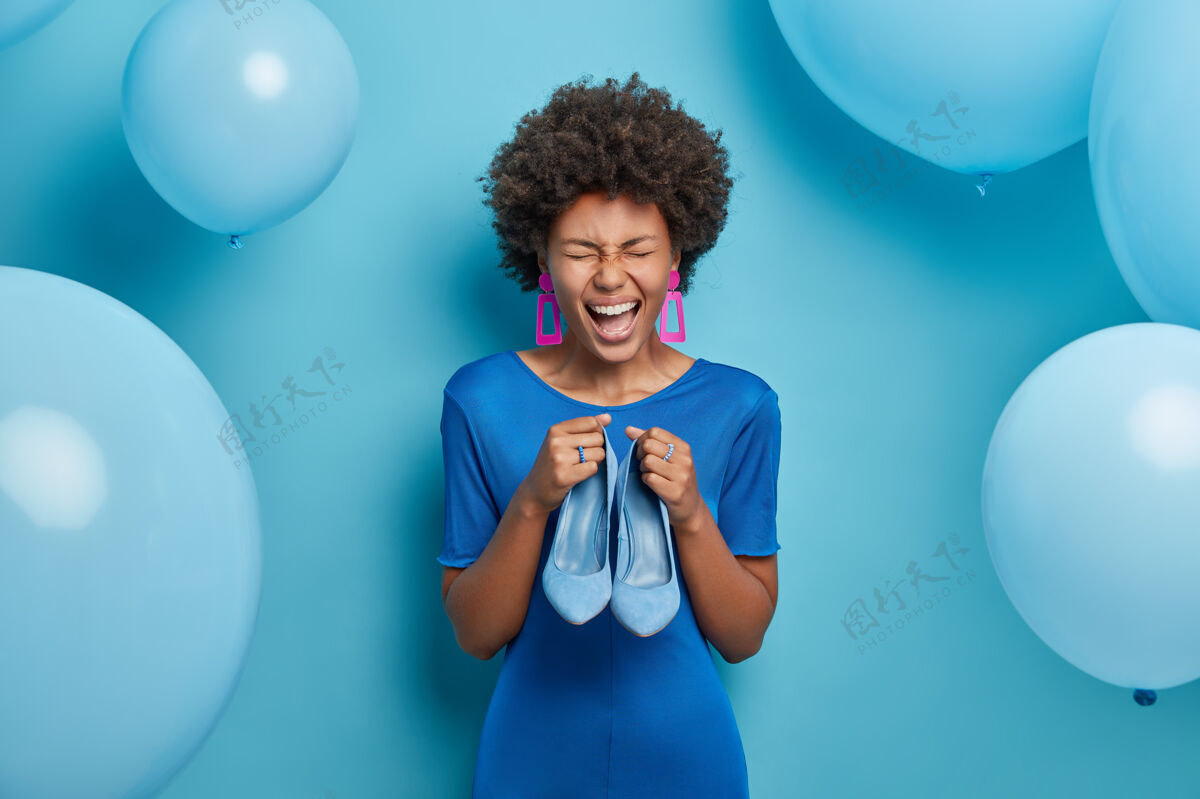 节日图为喜洋洋的女士喜购新装 手拿蓝色时尚鞋搭配礼服 在特殊场合穿着 去庆祝生日蓝色占上风时尚和服装理念高兴乐观高兴