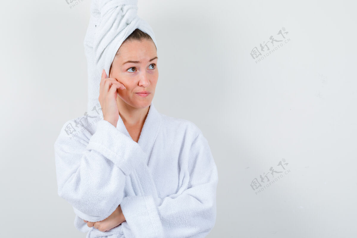干净穿着白色浴袍的年轻女士 手握毛巾贴在脸颊上 看起来很难看 正前方模特亚洲人浴袍