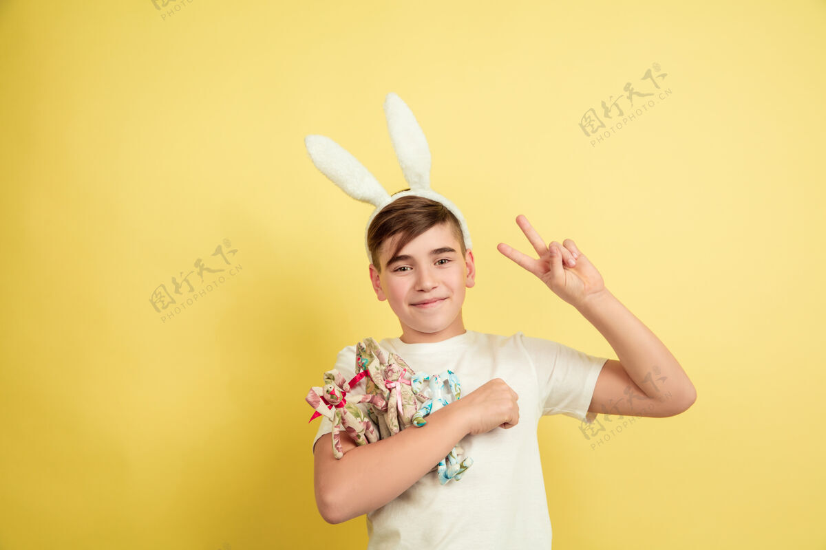 模型男孩像复活节兔子在黄色的工作室墙上帅气鸡蛋自信