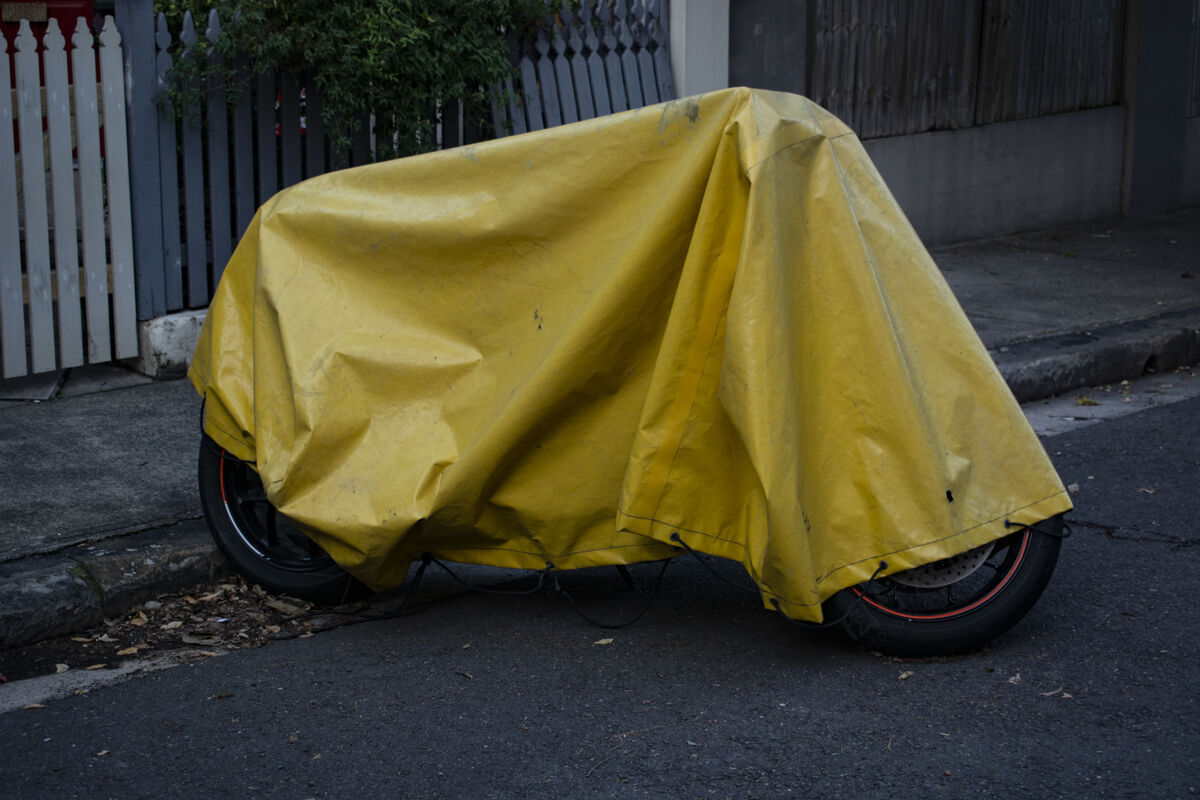 自然黄色的油布盖在一辆停在街上的摩托车上速度封面摩托车