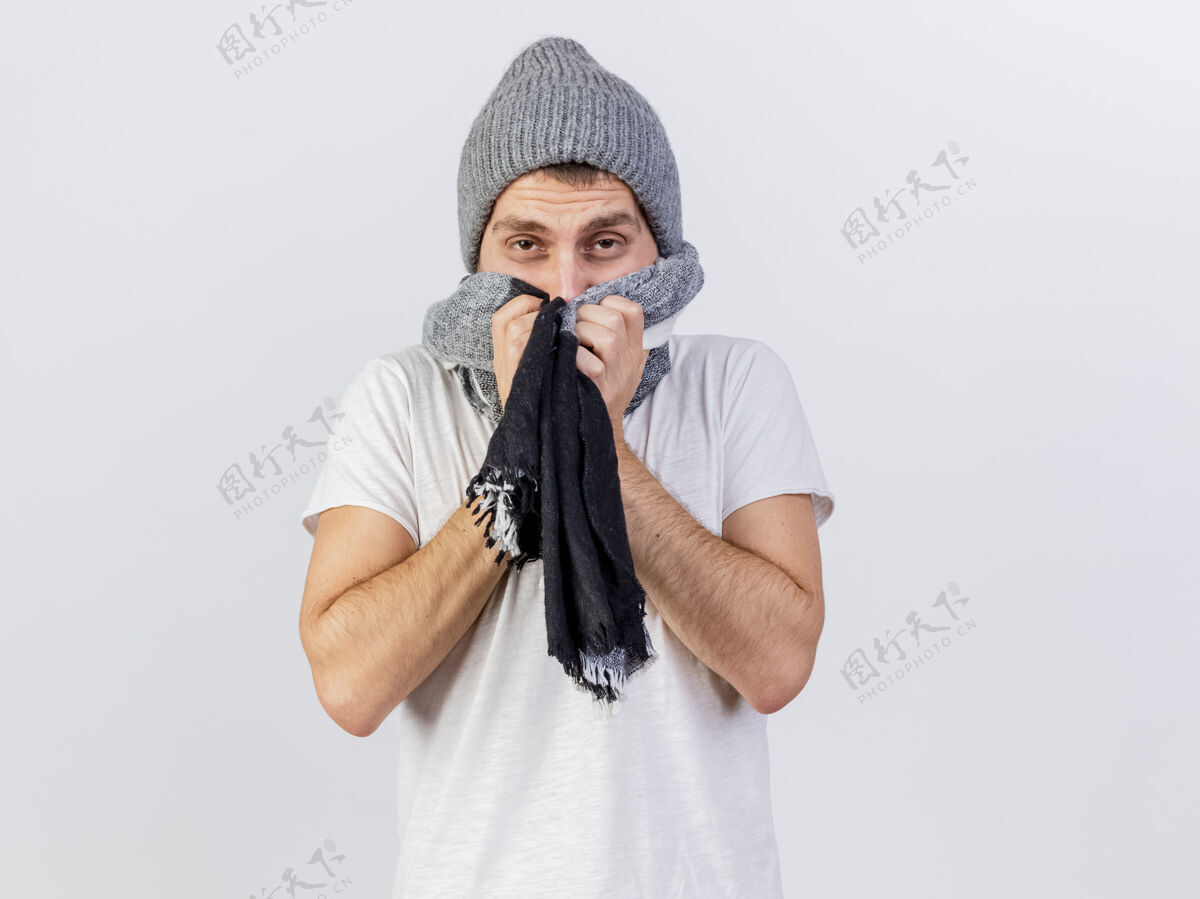 穿寒风凛冽的年轻病夫戴着冬日的帽子和围巾 脸上用围巾隔离着白色覆盖冬天年轻