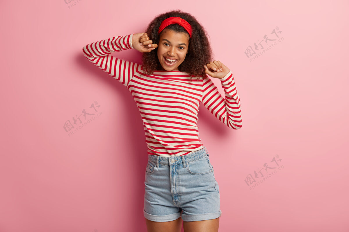 条纹美丽快乐的少女卷发摆在红色条纹毛衣积极女人移动