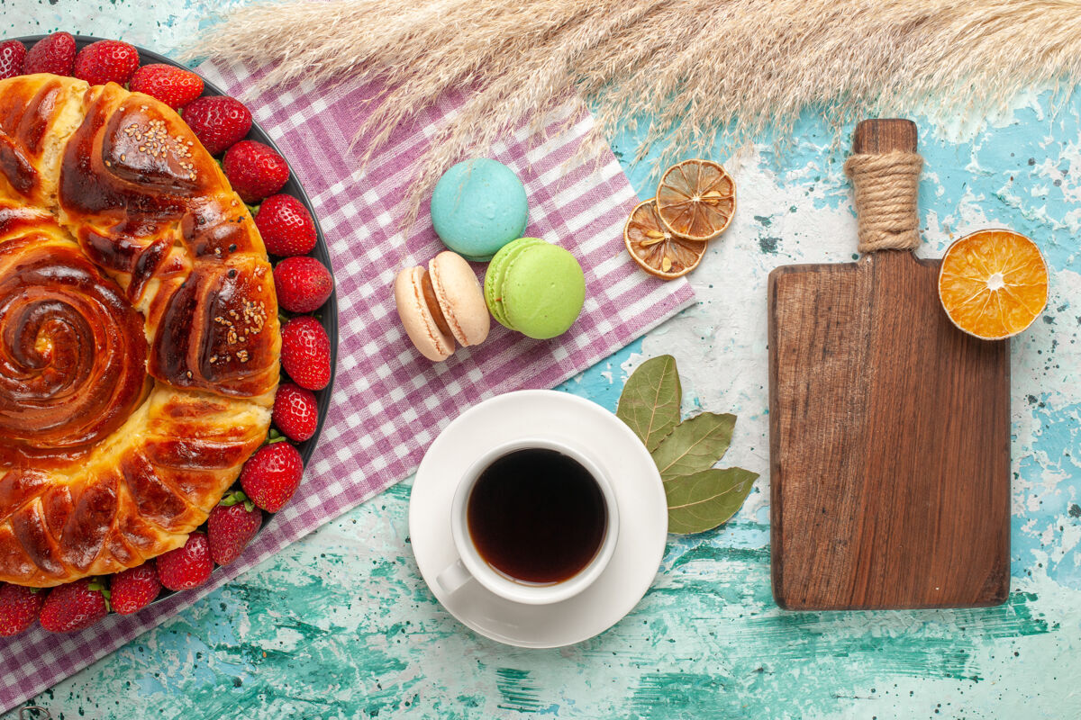 盘子俯瞰美味的派与红色草莓和一杯茶在蓝色的表面顶饮料早餐