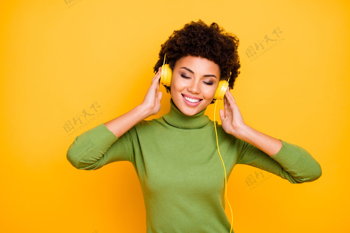 耳机她的肖像她好看迷人可爱欢快的棕色波浪发女孩听着清凉的音乐旋律非洲年轻卷发