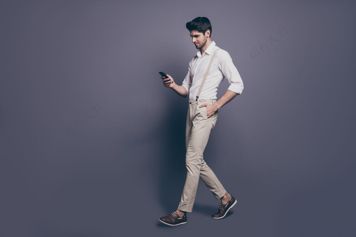 男士有魅力的奢侈男人的全长侧边肖像去文案空间散步使用智能手机聊天博客追随者秘密崇拜者穿好看的衣服年轻裤子信息