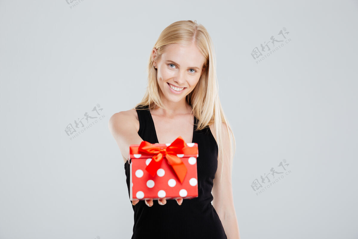 女士一个微笑的女人的肖像穿着裙子拿着礼品盒隔离在白色背景上高加索年肖像