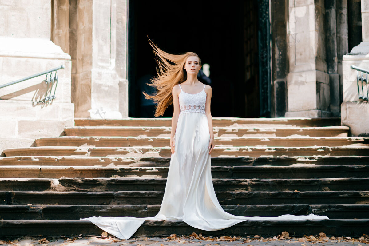优雅年轻优雅的女孩 一头飘逸的白发 身着白色长裙 在古宫殿的楼梯上摆着姿势女孩姿势模型