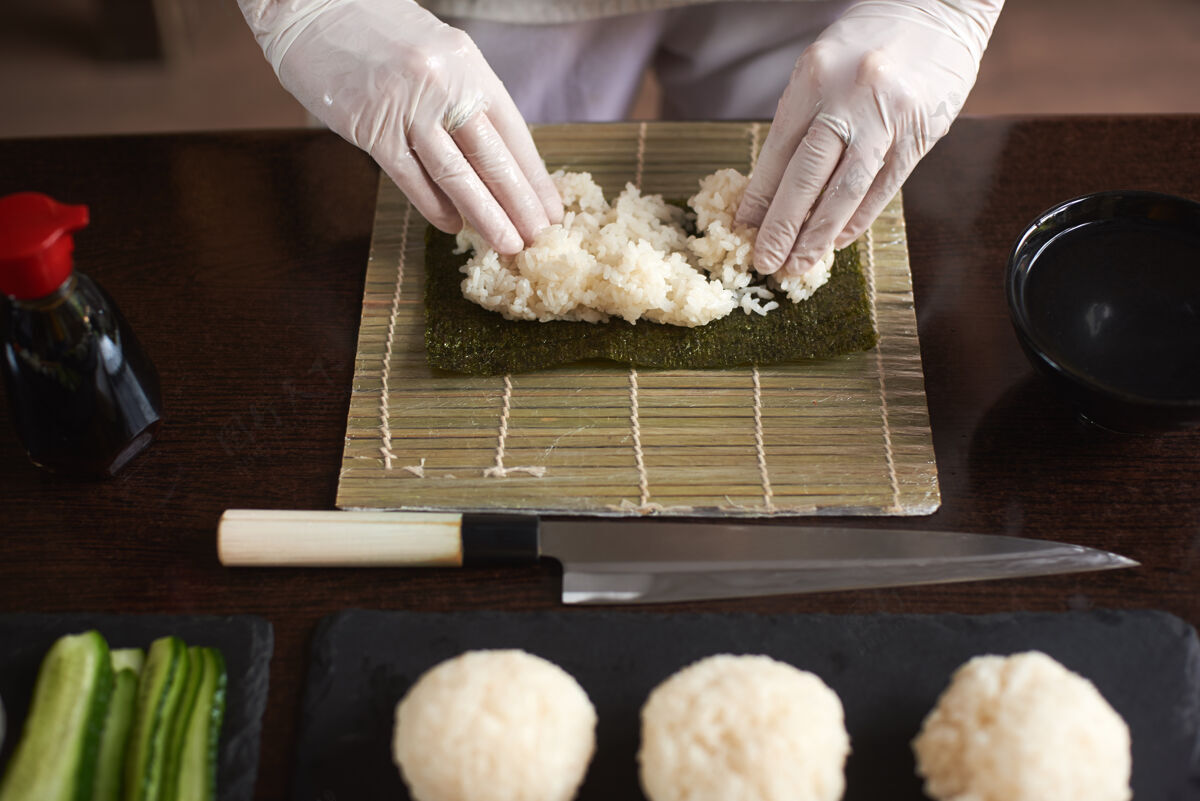 黄瓜制作卷寿司过程的特写镜头诺丽和白米厨师的女人用手触摸米饭厨师开始做寿司卷生鱼片酱油