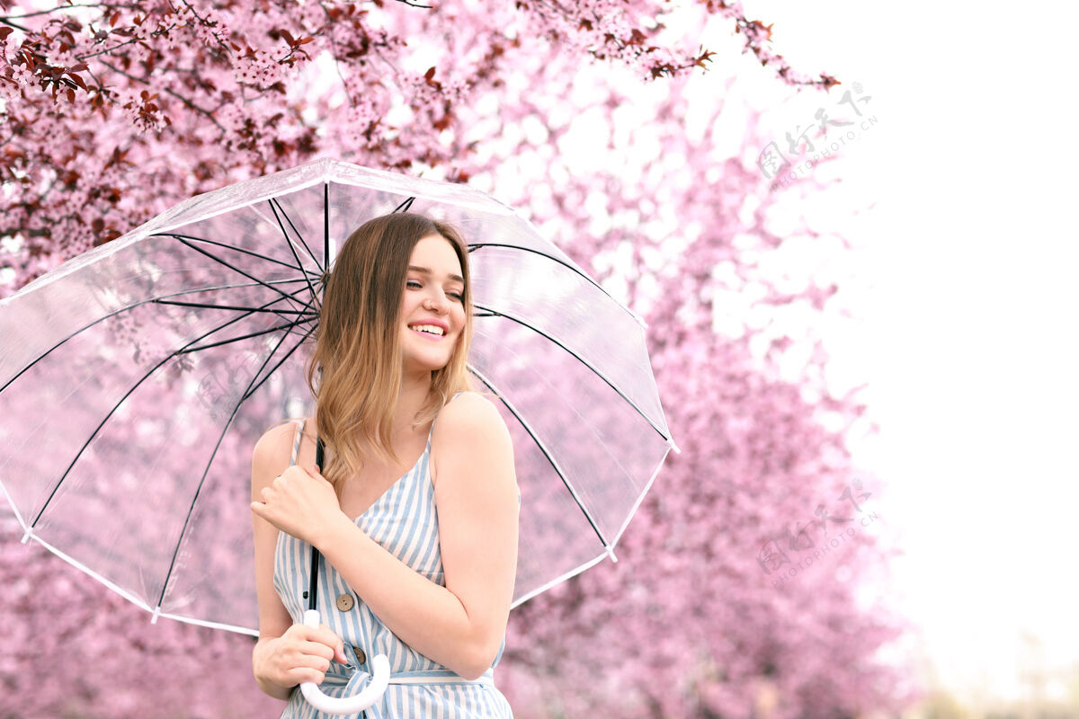 花园春日公园里带着雨伞的美丽年轻女子的画像花模型日