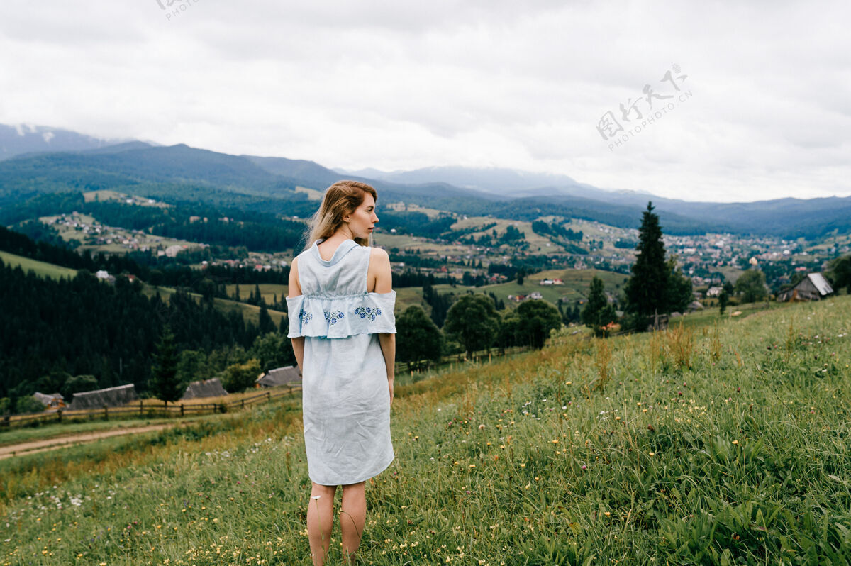 乡村年轻迷人优雅的金发碧眼女孩 身着蓝色连衣裙 在如画的风景上摆姿势田野优雅蓝色连衣裙