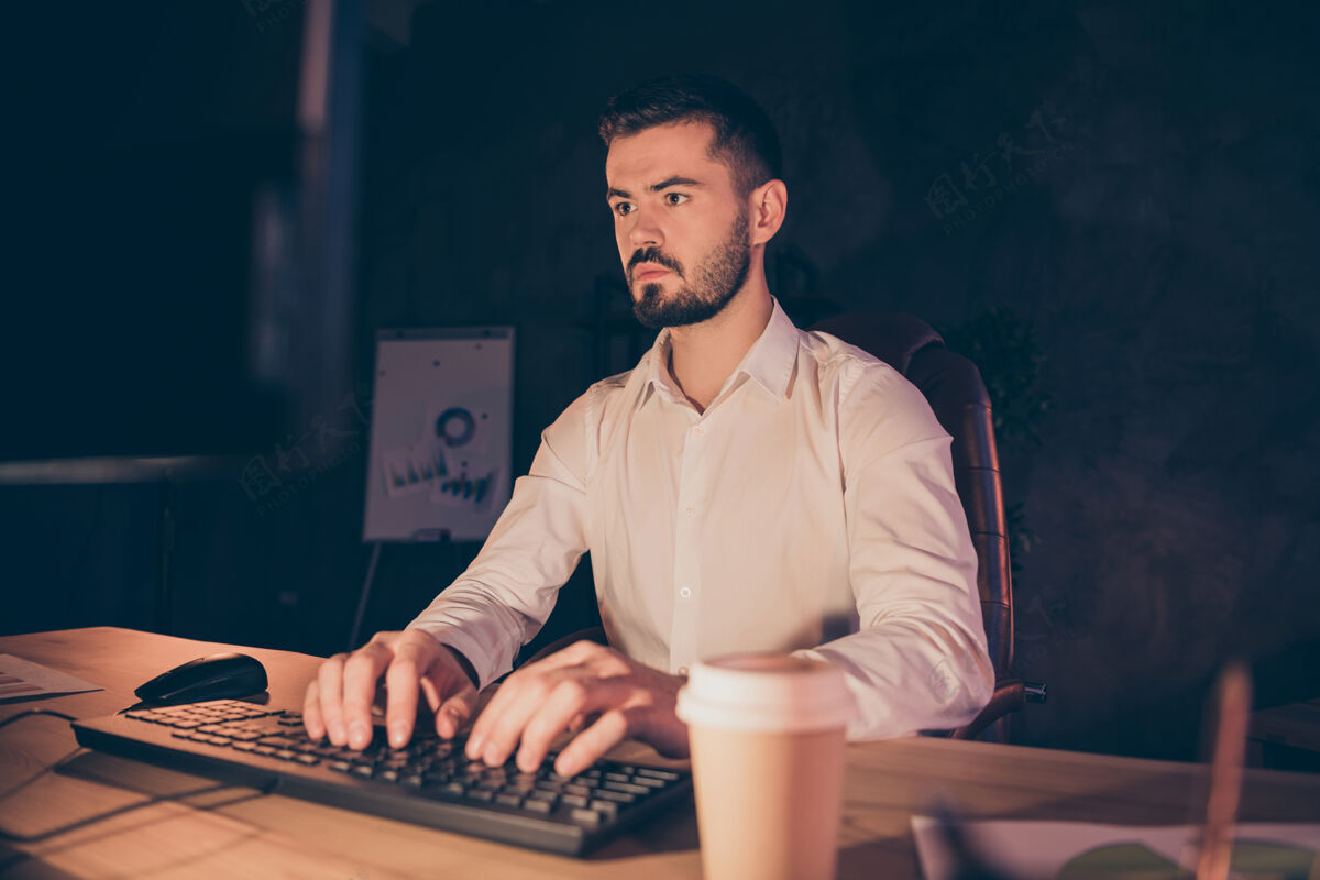 工作站专心致志的商人的画像晚上呆在黑暗的办公室里用电脑工作加班办公室年轻