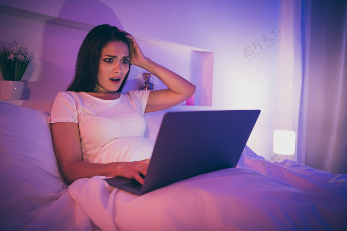 笔记本电脑可爱迷人紧张困惑的女人躺在床上使用笔记本电脑的画像房子晚上午睡