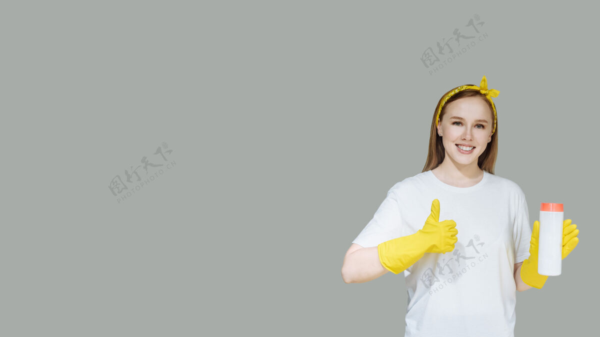 女人年轻的微笑女孩与家庭清洁用品的女佣手套女孩肖像