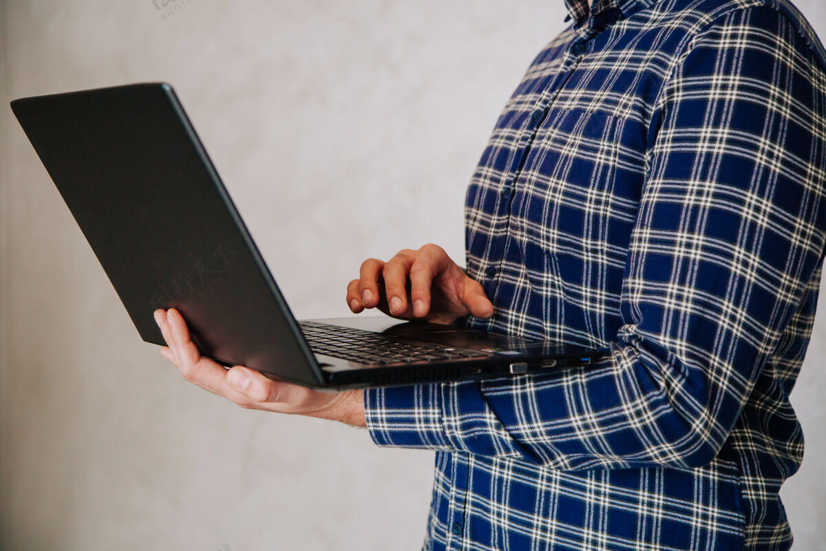 笔记本电脑黑发的年轻人手里拿着一台笔记本电脑商业理念在家工作个人电脑男人