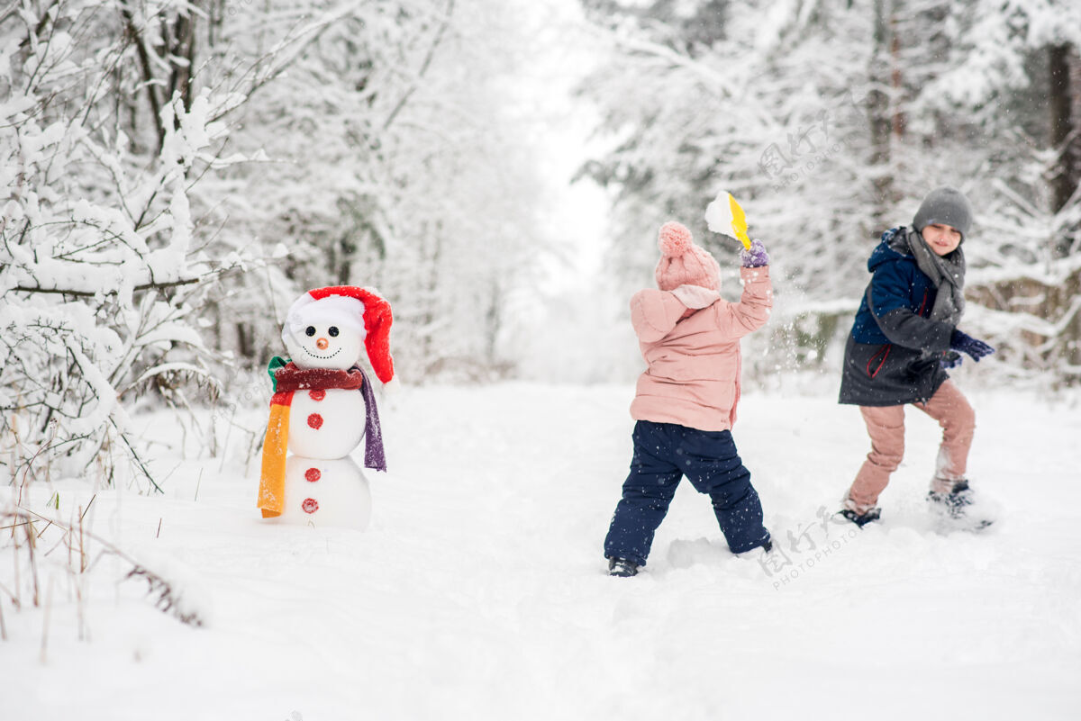 女孩可爱的男孩和女孩在冬天的白森林堆雪人冬天霜冻男孩