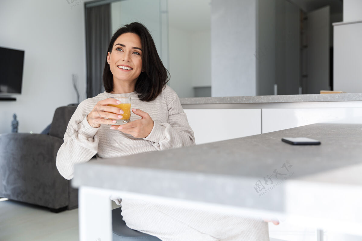 饮料30多岁的成熟女人一边喝着橙汁 一边在明亮的现代房间里休息居住女士深褐色
