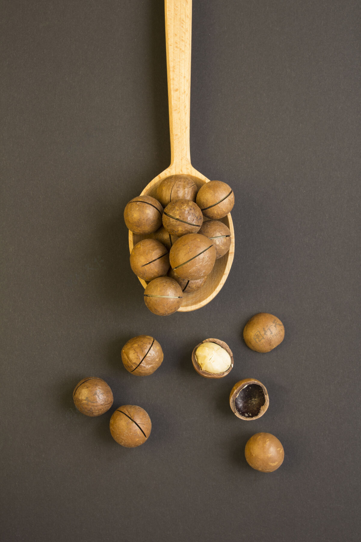 超级食品黑色表面木勺中澳洲坚果的俯视图位置垂直木勺位置生的