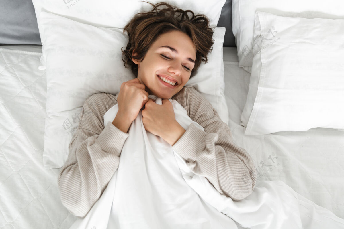 谎言一个微笑的年轻女孩在床上放松的俯视图吸引力床舒适