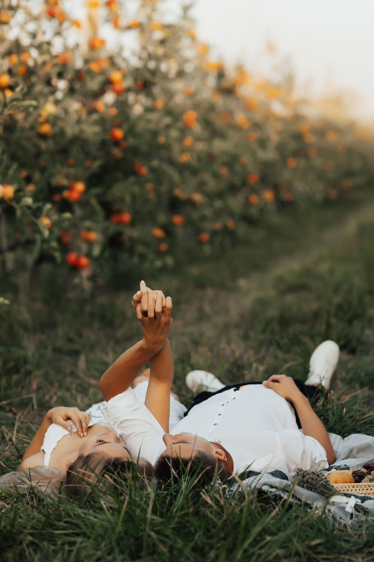 女孩躺在绿地毯上的迷人情侣草放松一对夫妇在夏天野餐衣服乡村树