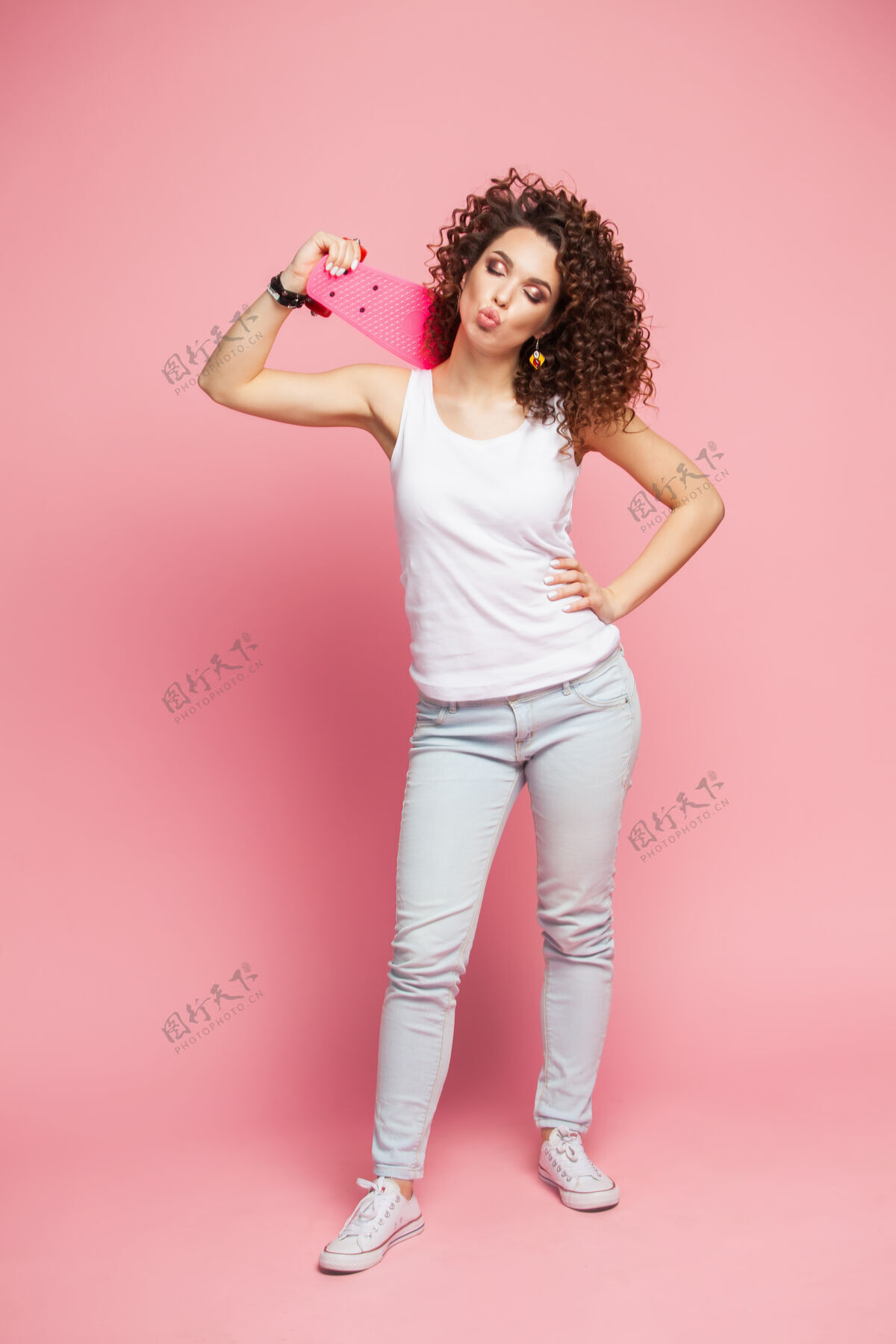 女性全高的搞笑时髦女孩与粉红色长板超过粉红色长板运动鞋短裤