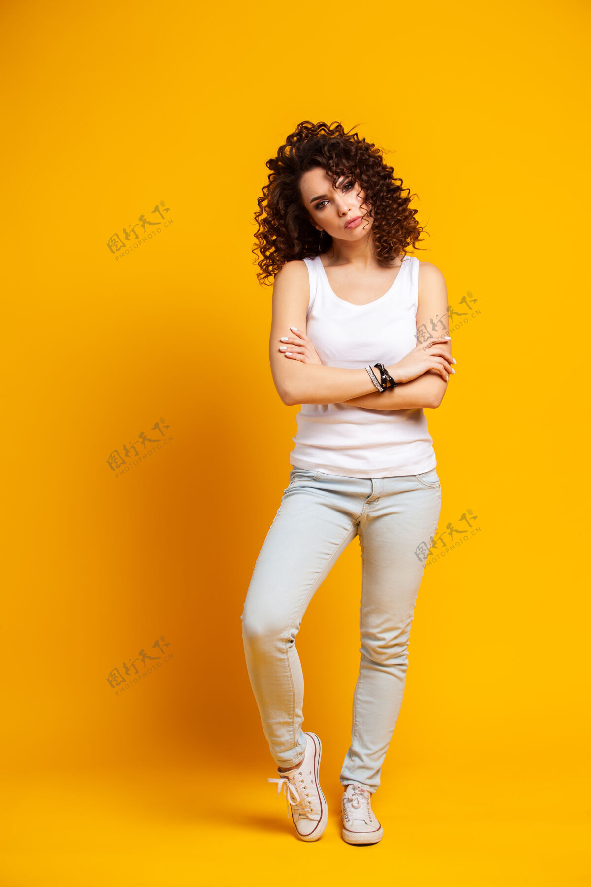 年轻一个微笑的休闲女人站在黄色的床上看着相机的全幅肖像站人女性
