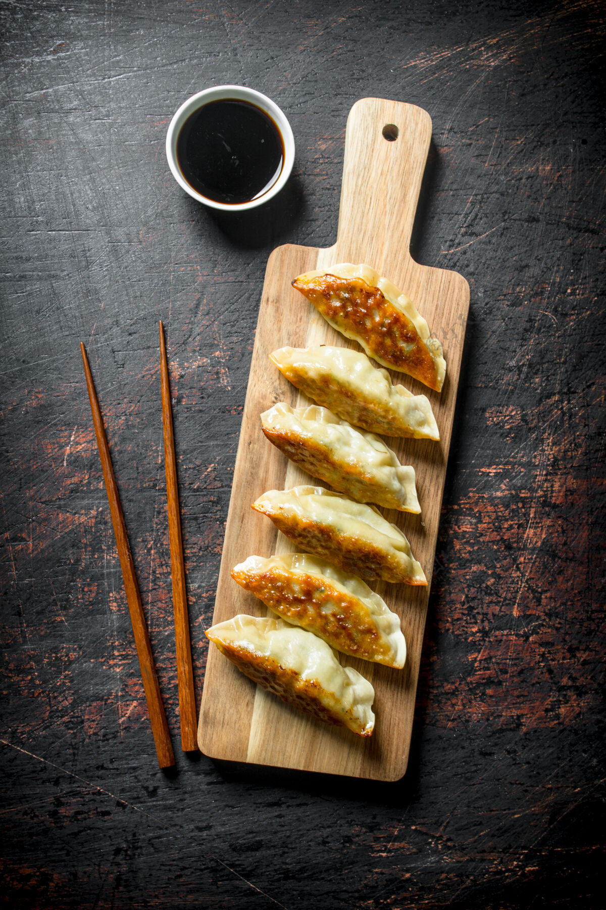 顶中国传统的盖扎饺子放在深色的乡村餐桌上的木制砧板上烹饪观点Gyoza
