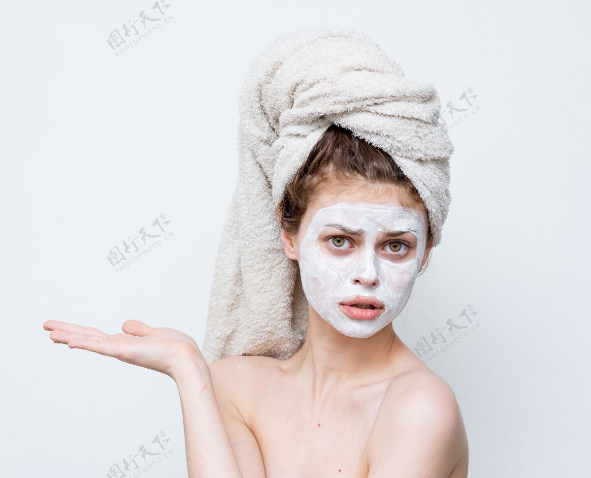 皮肤滑稽的女人 头上戴着毛巾 光着肩膀 脸上戴着白色面具面膜成人毛巾