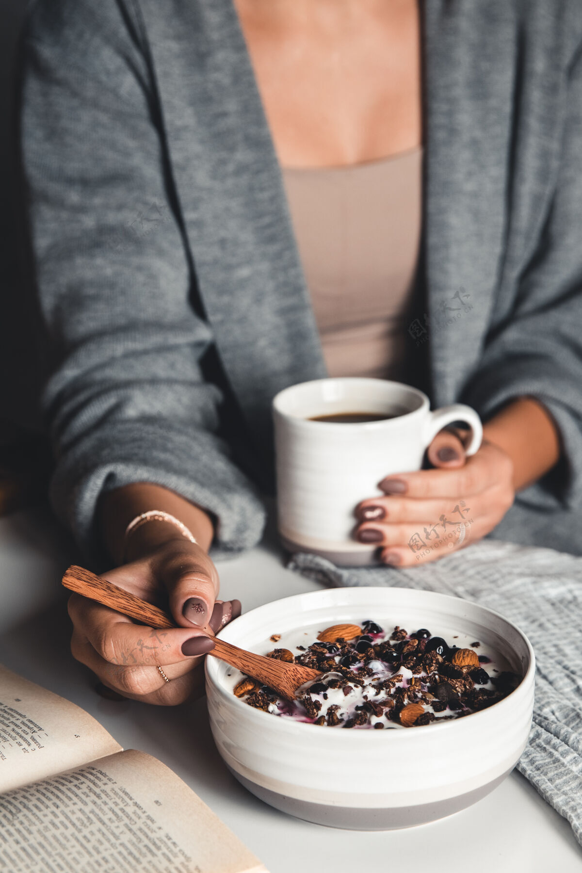 坚果一个年轻女孩喝早茶 吃健康的早餐 看书木头新鲜黑莓