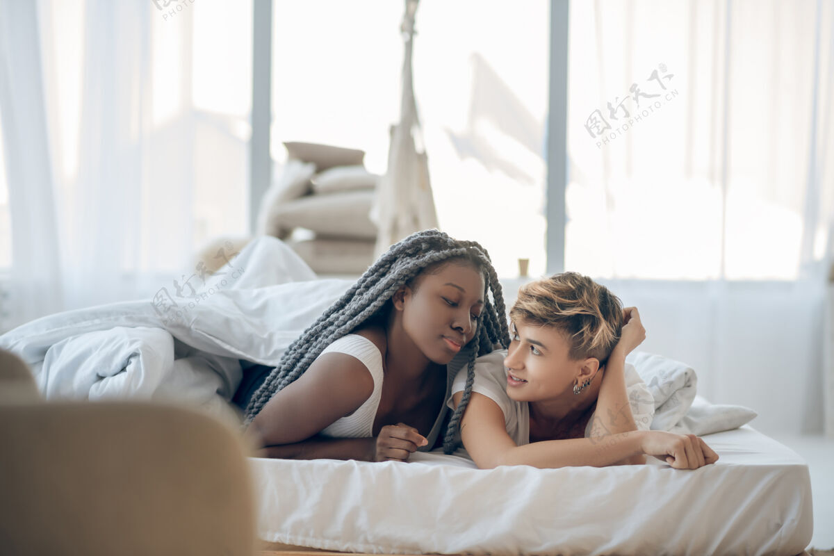 阁楼在爱二躺在床上感受爱情的女孩们舒适非裔美国人休息