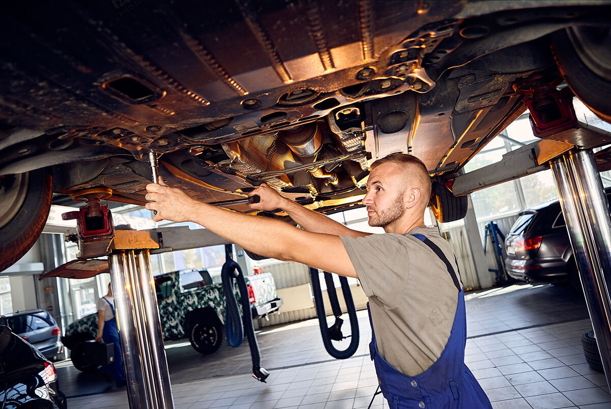 工作帅气的汽车修理工在加油站检查汽车的传动装置控制调谐技师