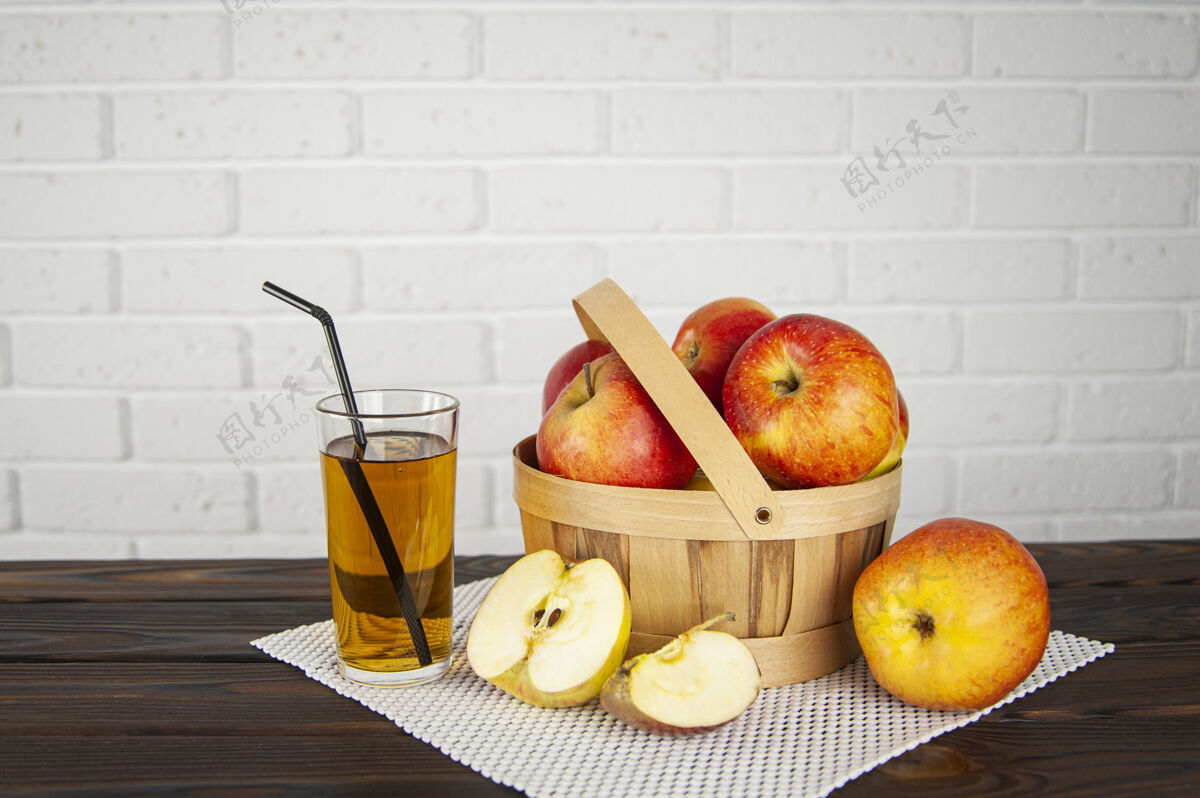 甜漂亮的苹果放在木制的篮子里 放在木制的表面上 还有一杯苹果汁水果果汁有机