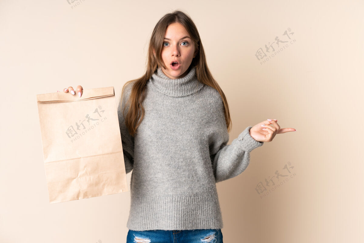 素食年轻的立陶宛妇女拿着一个购物袋惊讶地指着旁边女性健康饮食