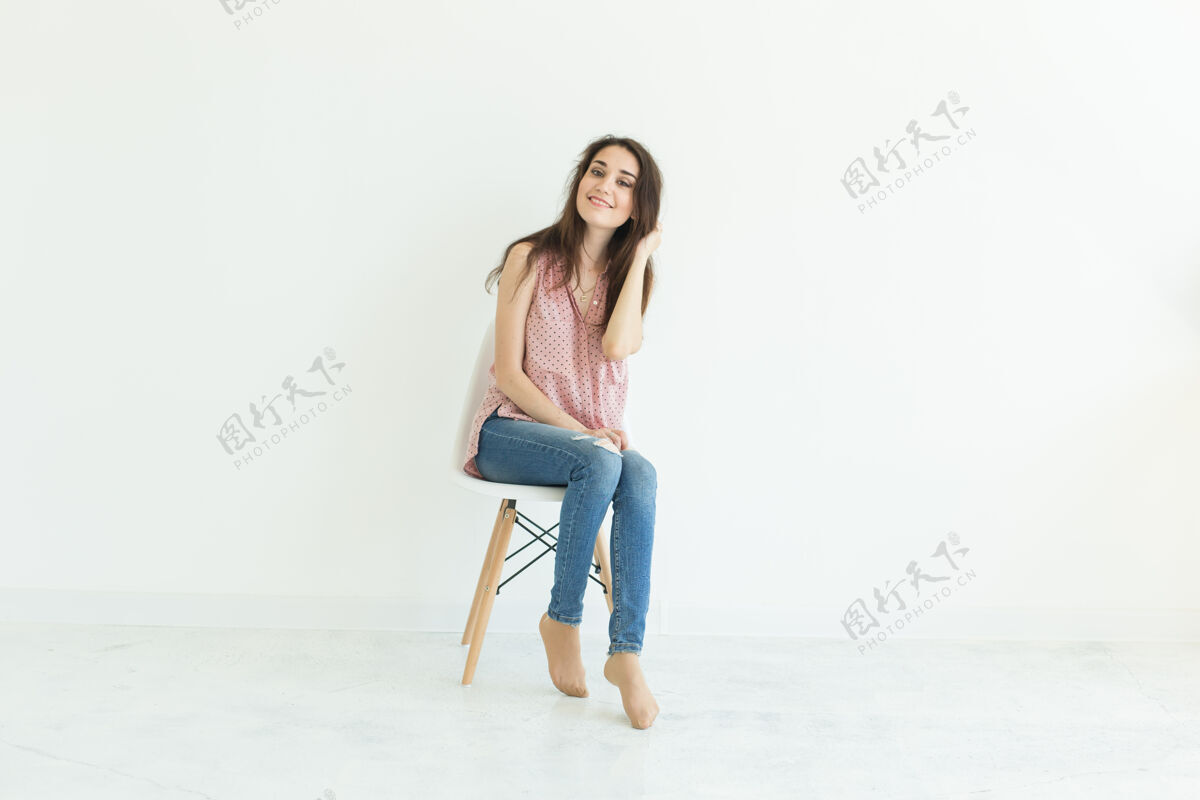 姿势坐在白色房间椅子上的年轻女士椅子单身模特