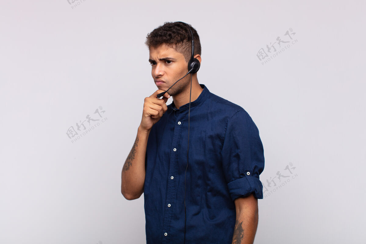 麦克风年轻的电话推销员思考 感到怀疑和困惑 有不同的选择 不知道该做哪个决定服务耳机担心