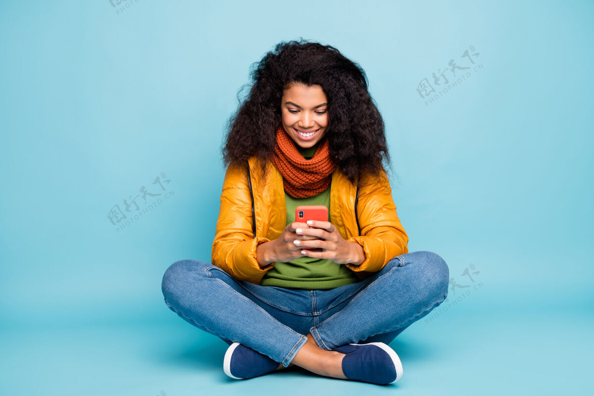 学生皮肤黝黑的女士在手机上浏览互联网蓝色背景隔离多民族民族蓝色背景