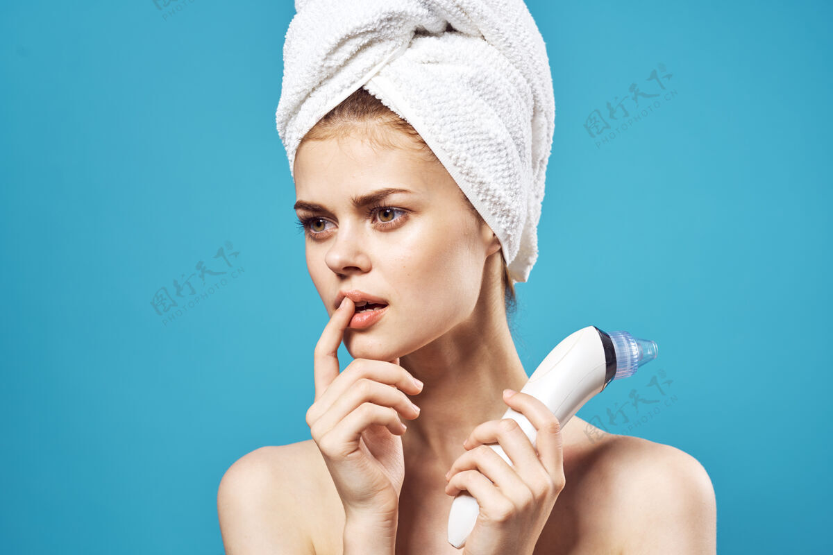 清洁漂亮女人光着肩膀用毛巾在头上按摩蓝色的墙壁面部护理皮肤科