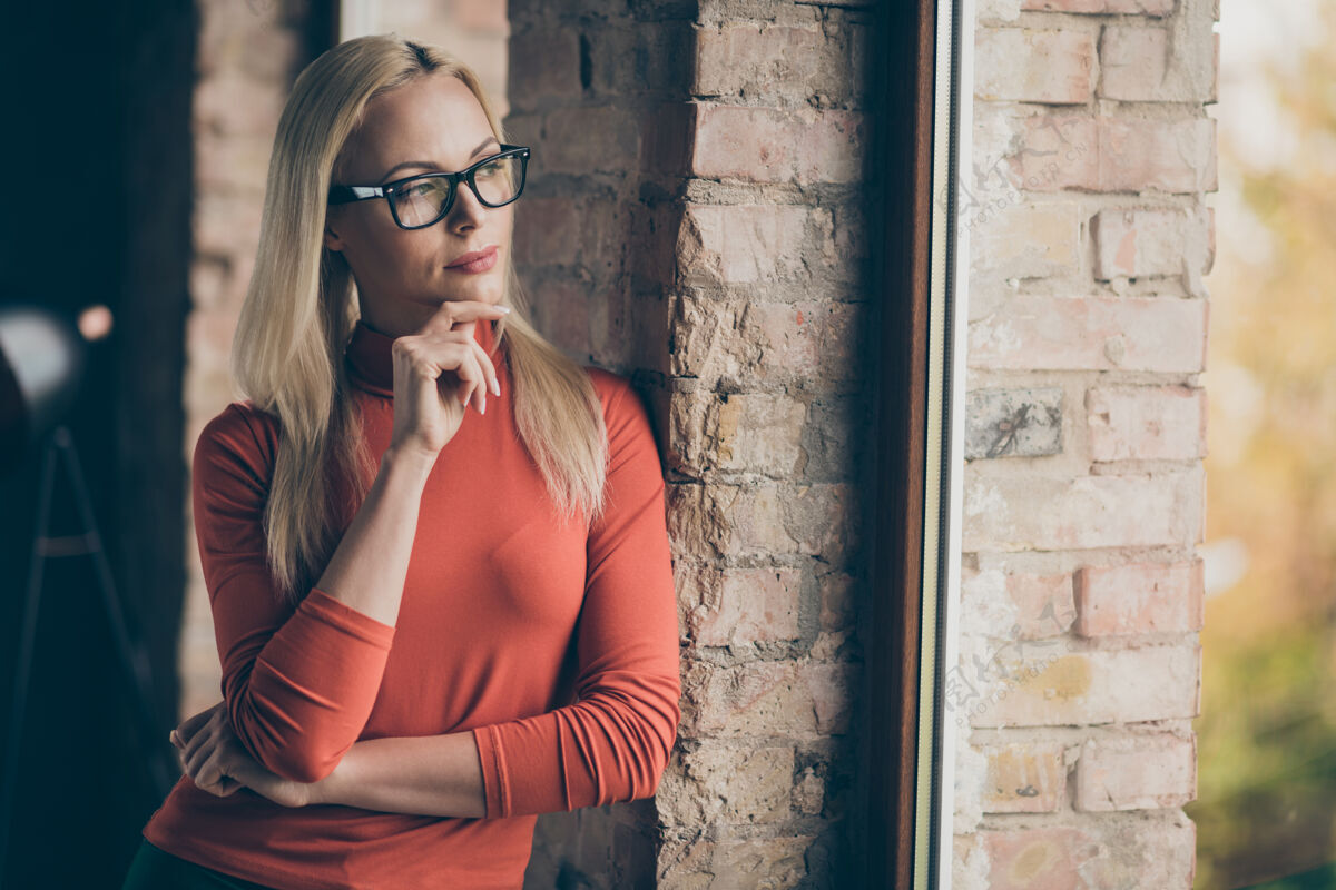 头脑风暴沉思的企业家迷人的女人站在窗口思考创业的想法选择决定决定在办公室阁楼穿红色高领毛衣工人执行官公司