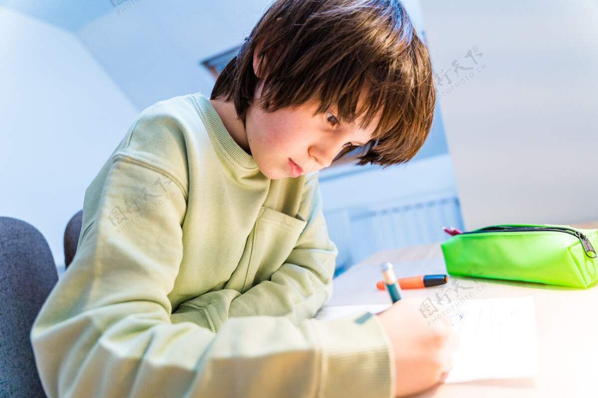 学校小男孩坐在桌子旁做作业家集中儿童写作家庭教育概念人锻炼注意力
