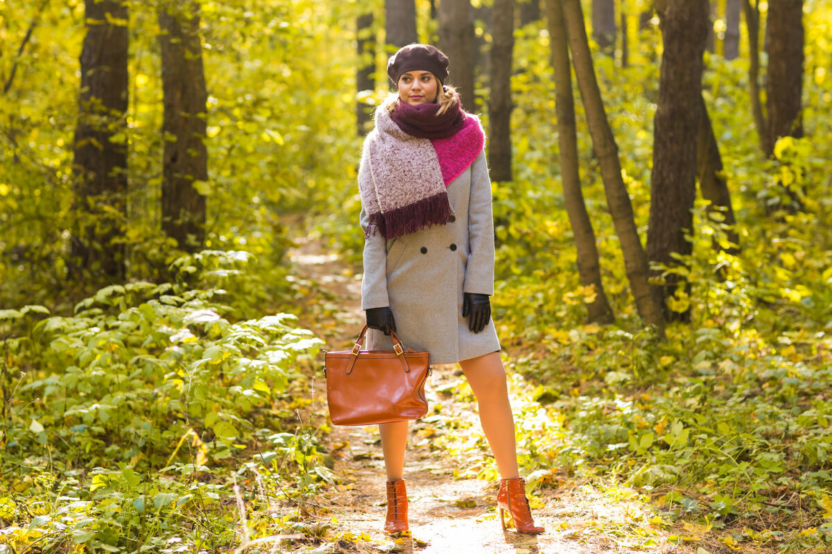 公园秋天公园里的女人拿着包摆姿势吸引力阳光灌木
